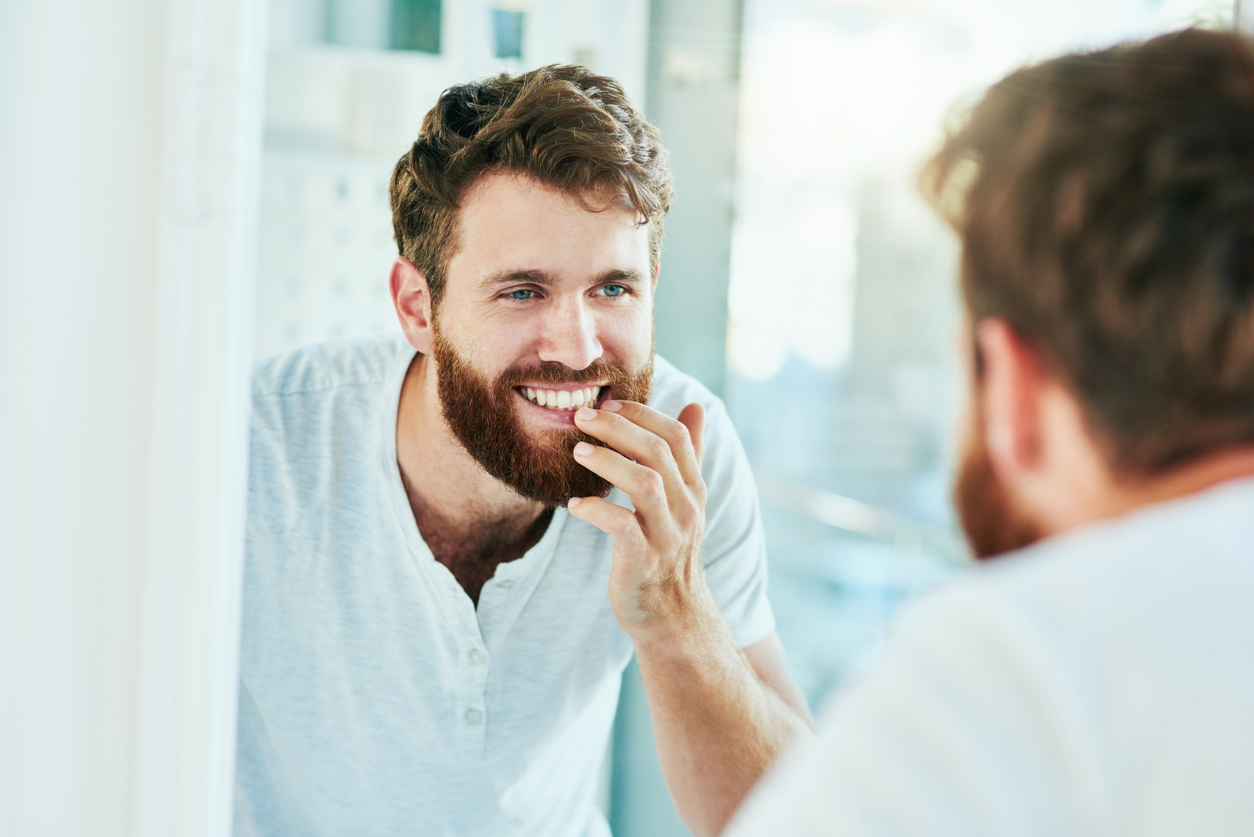Man with great smile examining his smile in the mirror