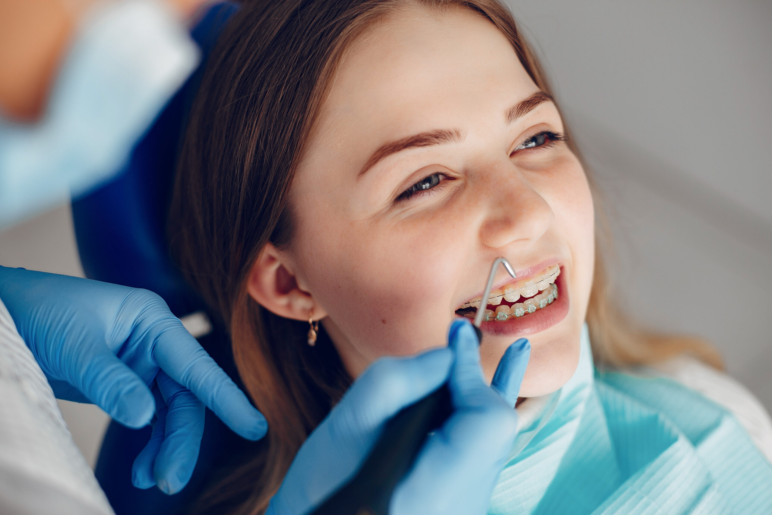 Young woman grinning up at her orthodontist while wearing a dental bib