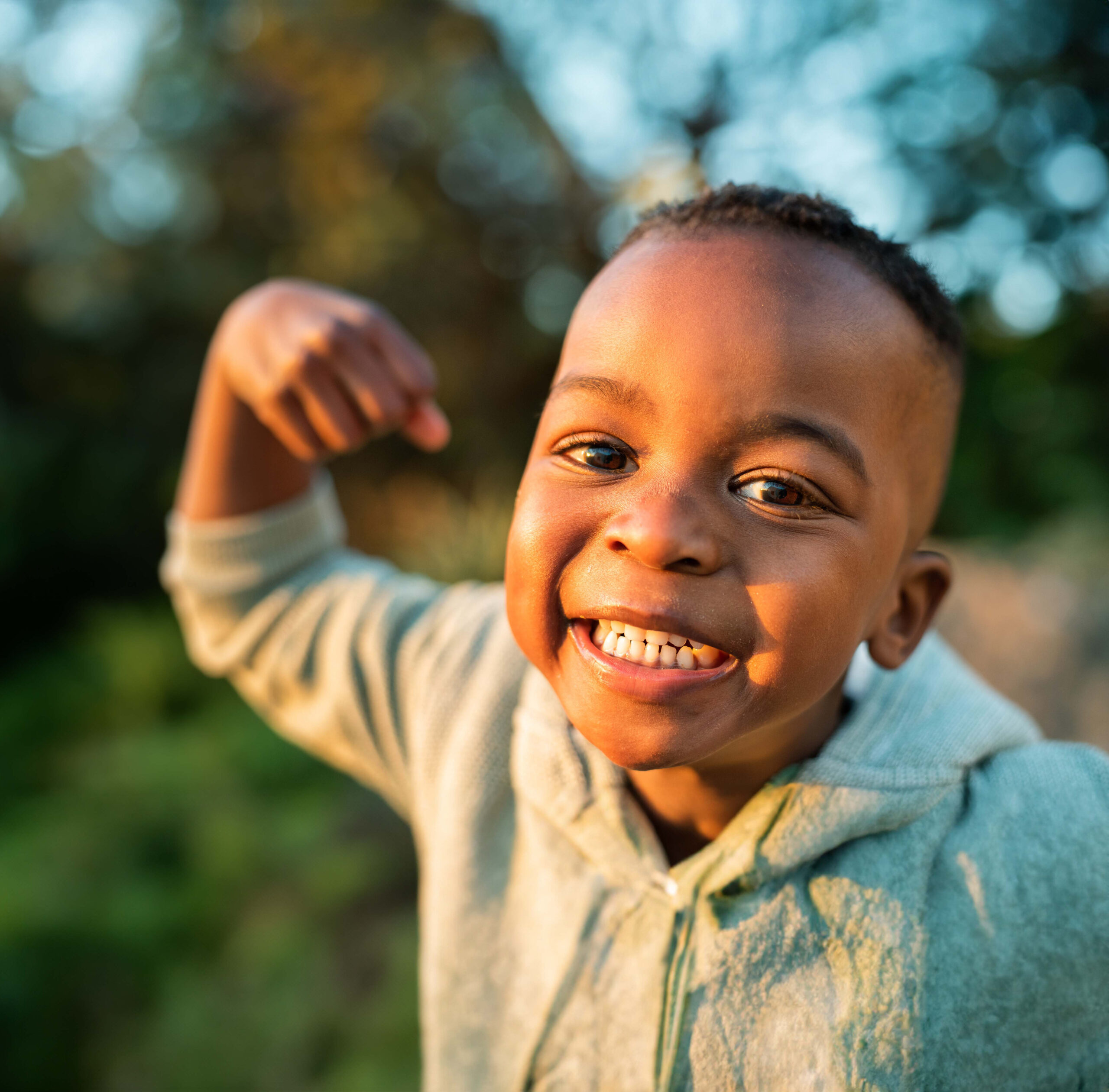 a little boy flexing his arm outside