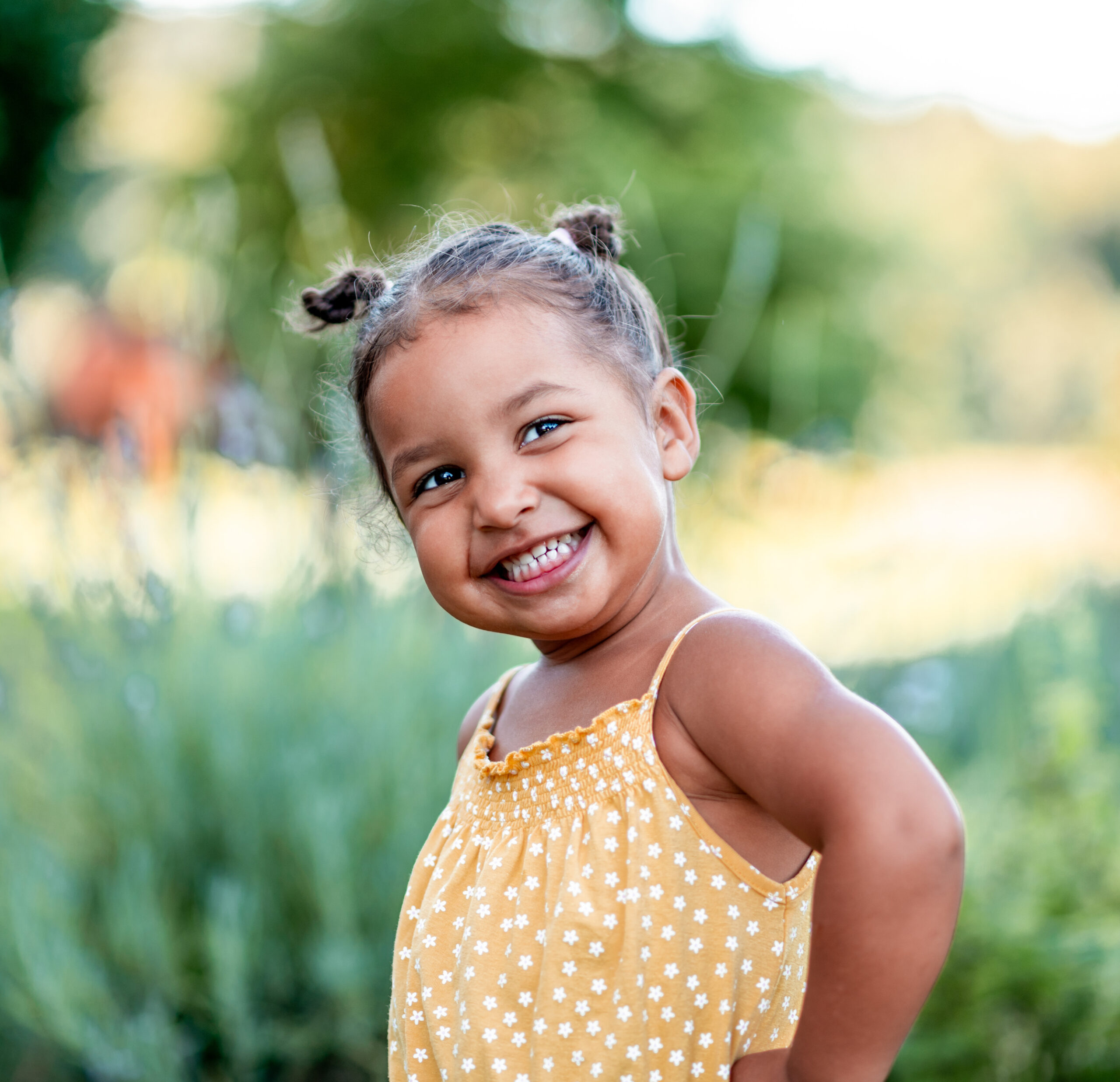 Portrait of a cute little cheerful mixed race girl in a yellow summer rummper.