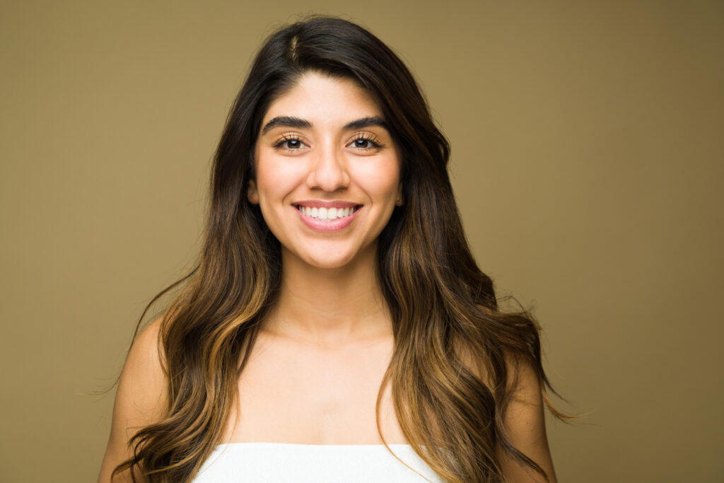 woman with dark hair smiling in front of a tan bronze backdrop