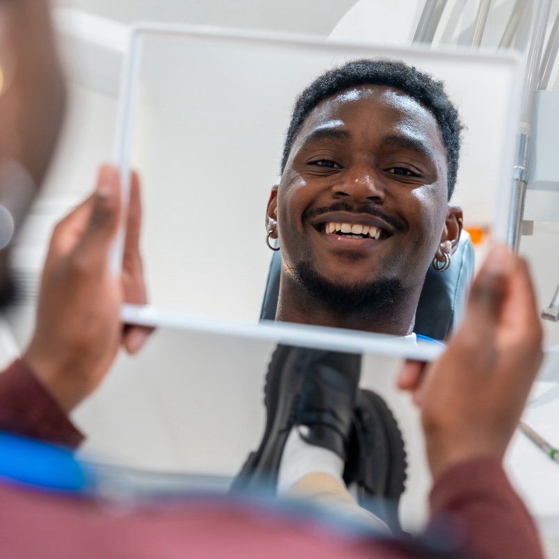 young man admiring his perfect smile during dental treatment